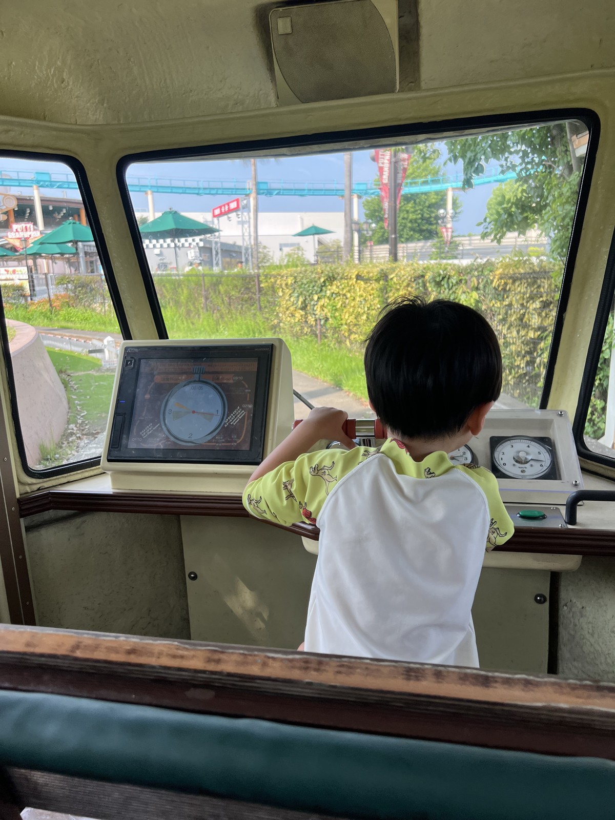 ボートの運転席で計器を見ながらハンドルを握る子ども