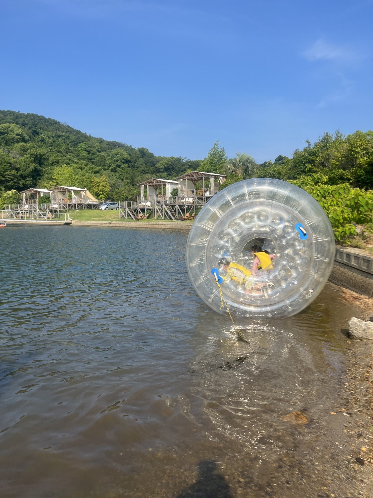 透明な水上ボールに入って水面を転がる子ども
