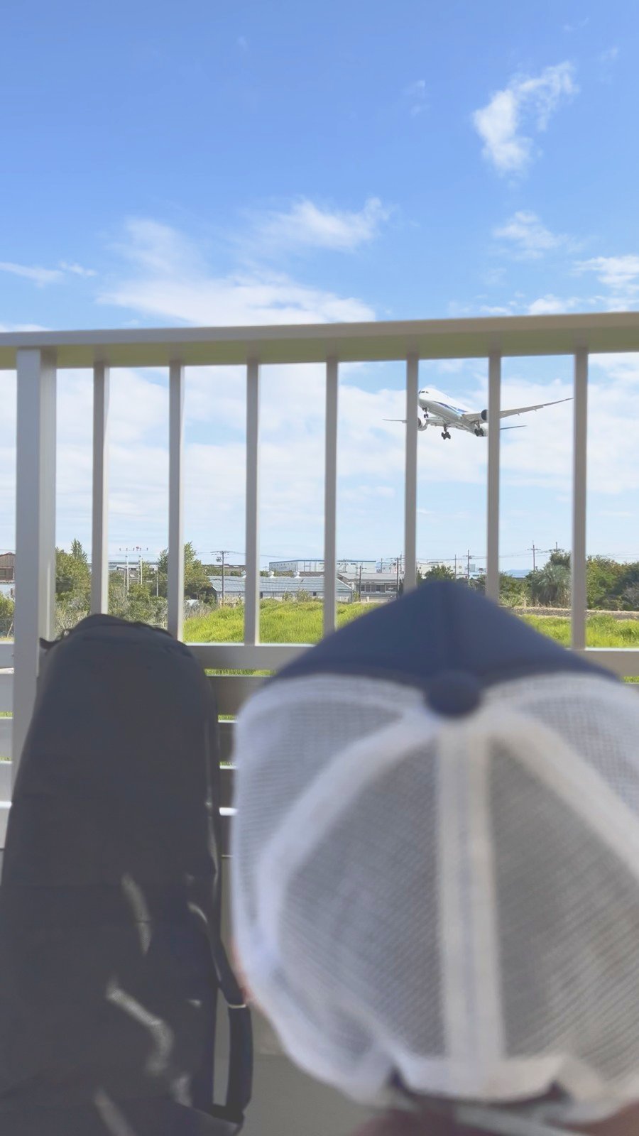 柵越しに着陸してくる飛行機を見る子ども