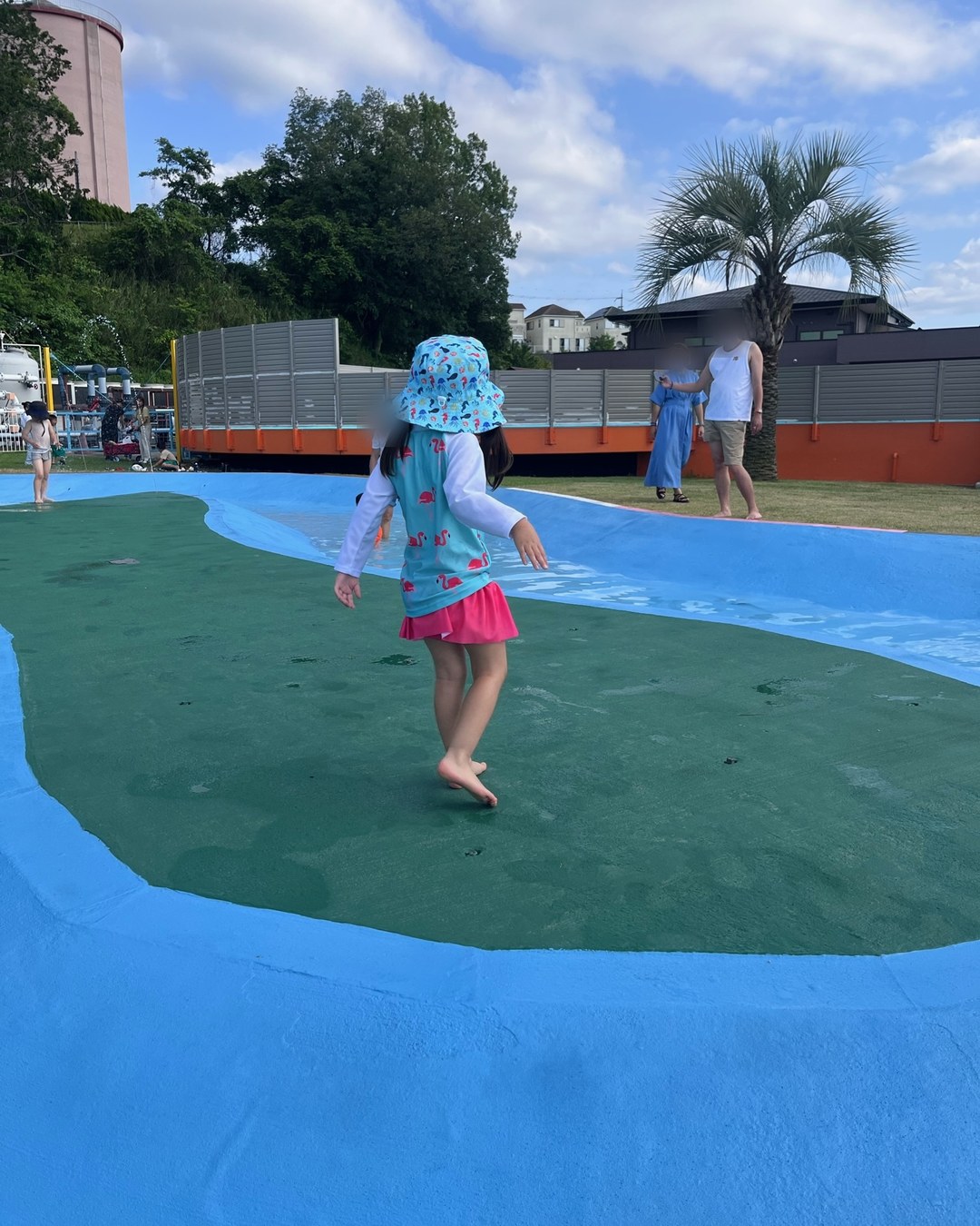 水色の床に張った浅い水の上を歩く子ども
