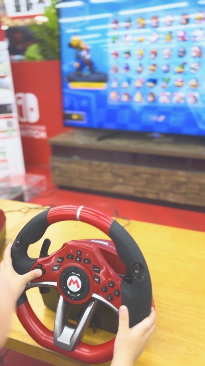 マリオのハンドル型コントローラーを握る子どもの手